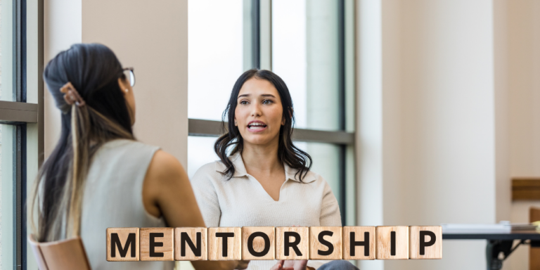 two women talking with letters spelling the word mentorship